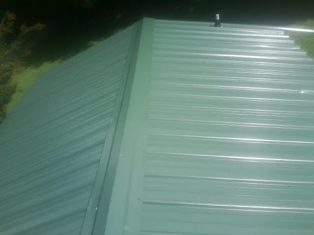 New green metal panels meeting at the ridge of a roof — Flat Roof Repair work by our crew in Maitland