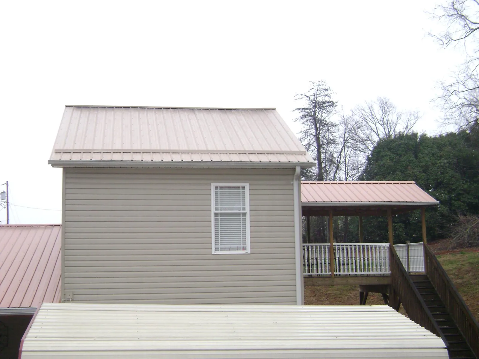 Tan metal roofs on a two story addition and attached porch, from a Roof Replacement job in Maitland
