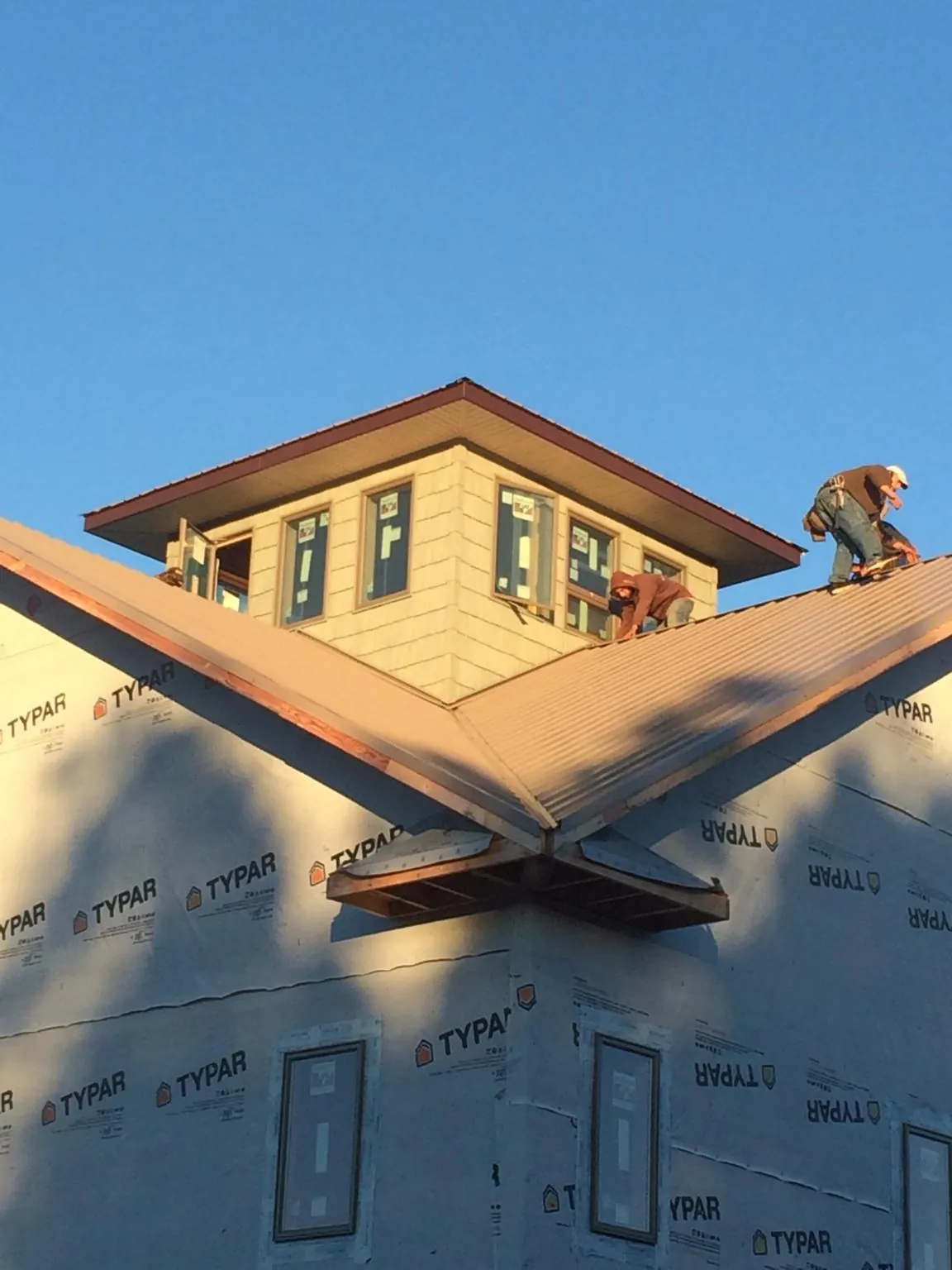 Roofers working around a rooftop cupola on a new metal roof at sunset — Roof Waterproofing in Maitland by Roofing Brothers